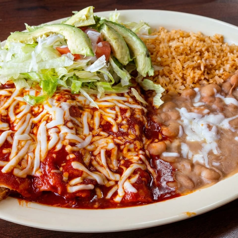 Mexican plate featuring cheese-topped enchiladas, refried beans, seasoned rice, lettuce, tomatoes, and avocado.